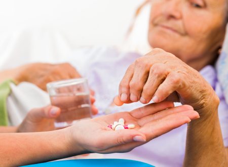 Homecare nurse helping elderly lady to take her daily medicine.